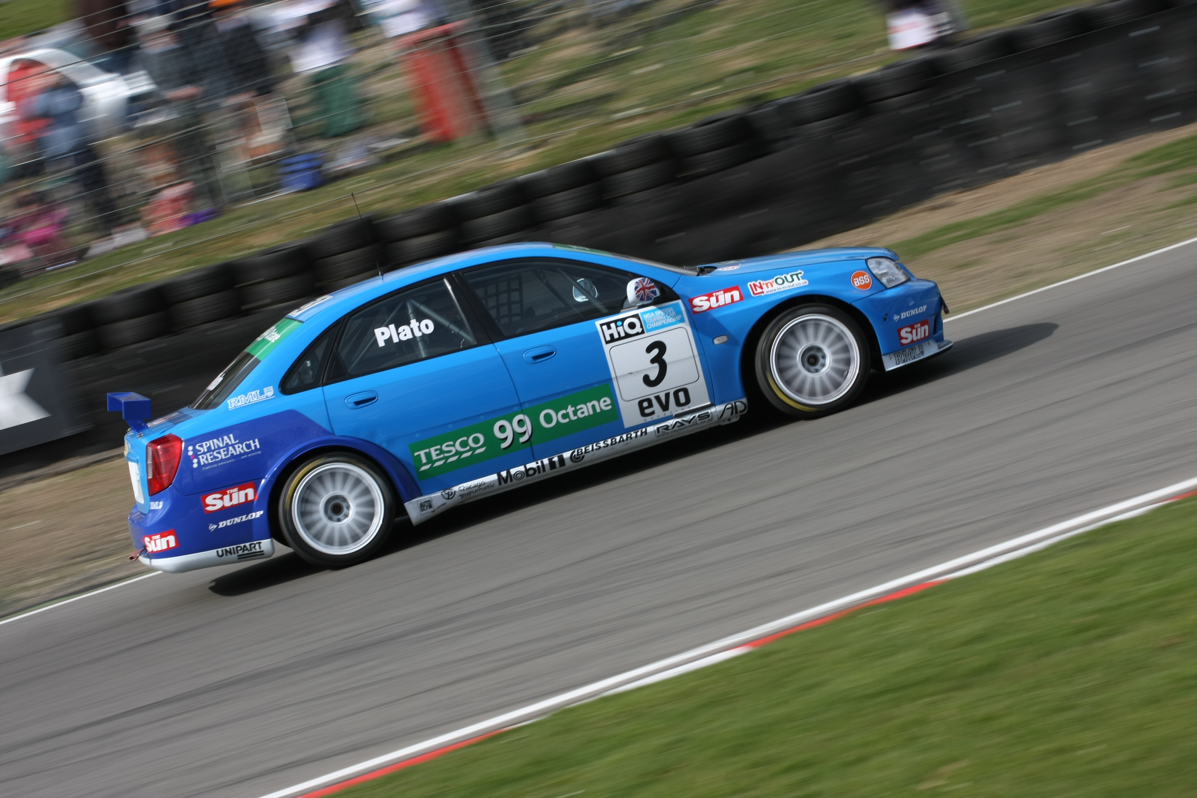 Front 3/4 photo of a white and light blue Infiniti Q50 in the pitlane at a damp Silverstone after a BTCC round