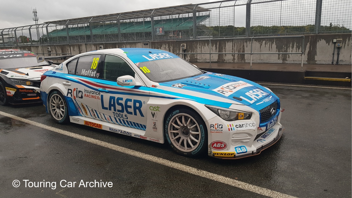 Front 3/4 photo of a white and light blue Infiniti Q50 in the pitlane at a damp Silverstone after a BTCC round